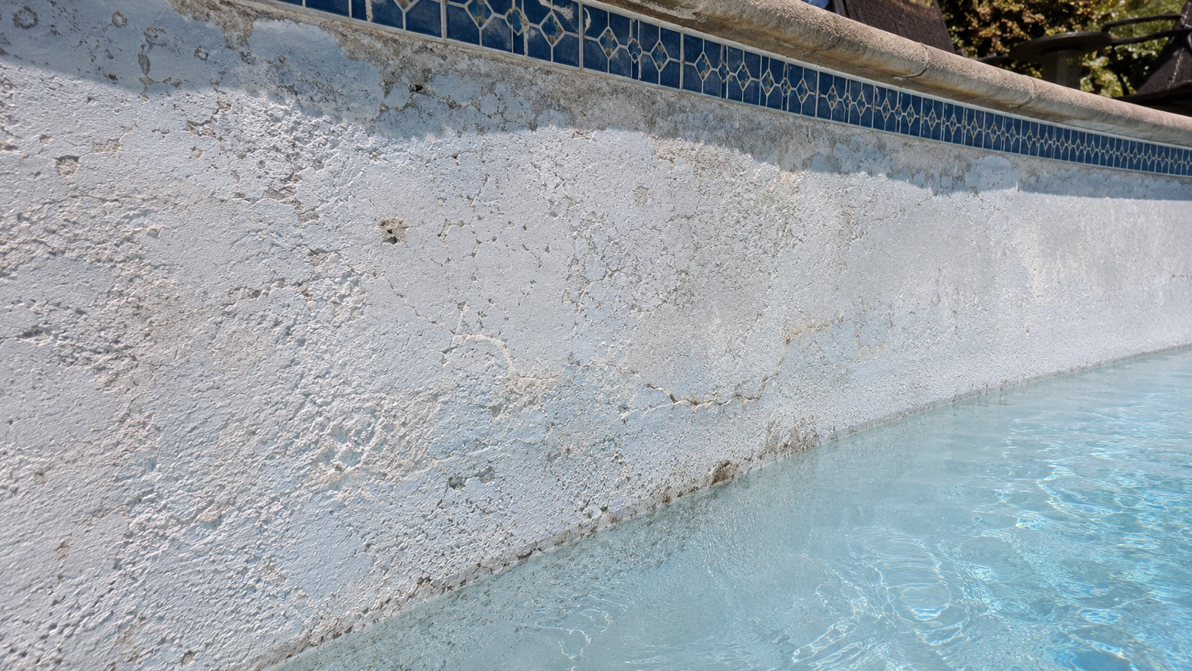 image showing close-up detail of cracked, stained, or deteriorating pool plaster before restoration